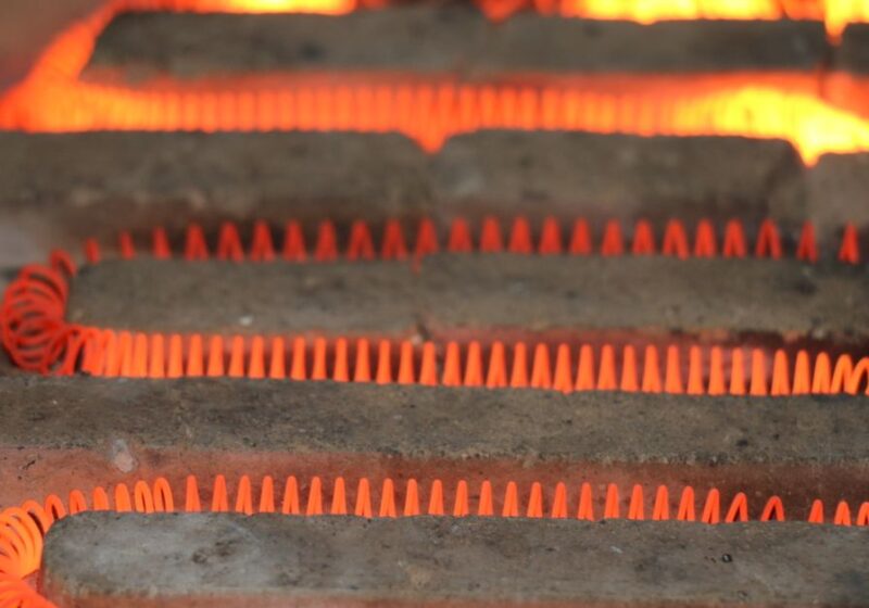 Detailed view of a glowing electric heating element with a coiled structure emitting heat.