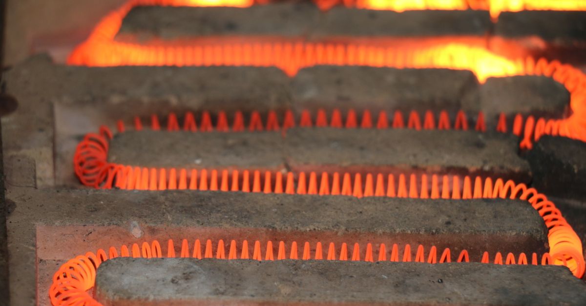 Detailed view of a glowing electric heating element with a coiled structure emitting heat.