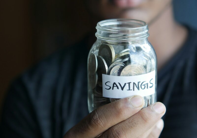 a man holding a jar with a savings label on it