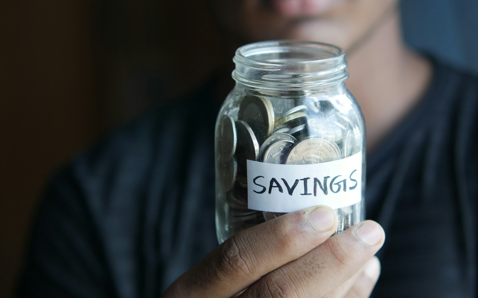 a man holding a jar with a savings label on it