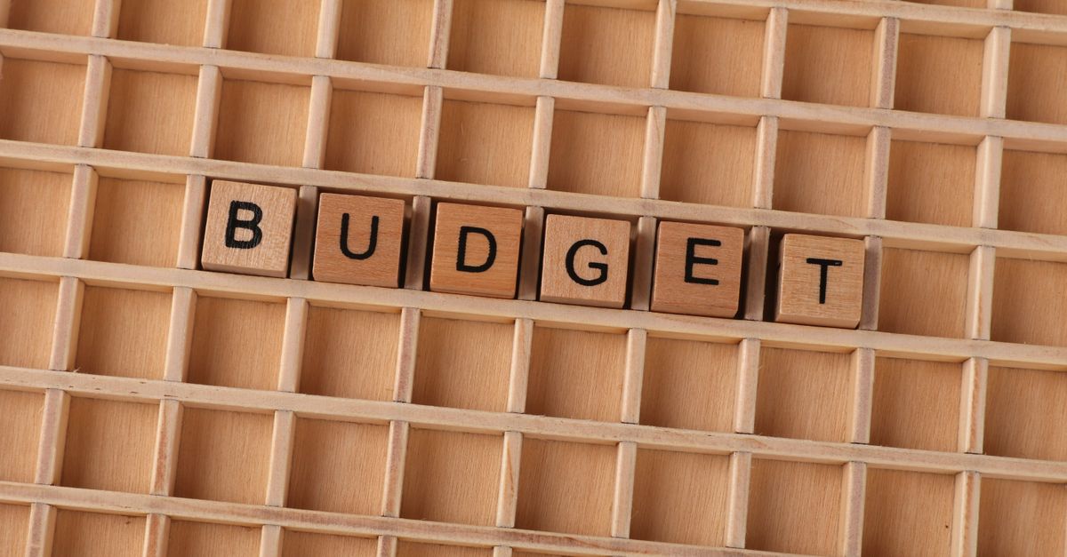 Wooden Scrabble tiles spelling 'budget' on a textured wooden grid, symbolizing financial planning.