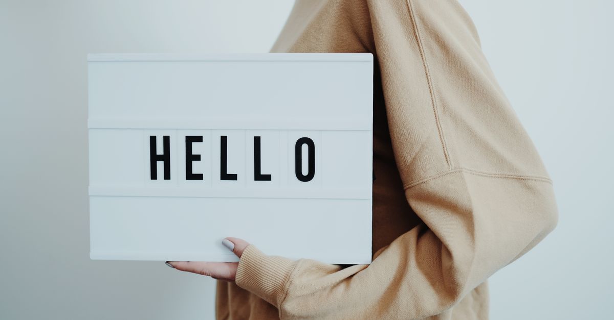 A person holding a lightbox displaying the word 'HELLO' on a white background.