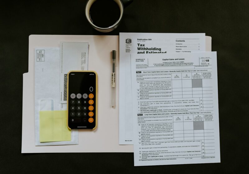 black Android smartphone near ballpoint pen, tax withholding certificate on top of white folder