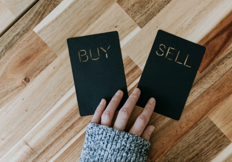 a person holding two small black books with the words buy and sell on them