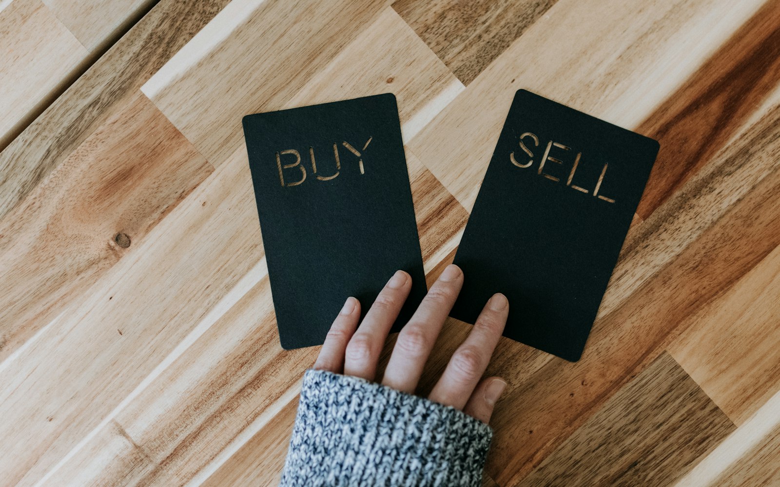a person holding two small black books with the words buy and sell on them