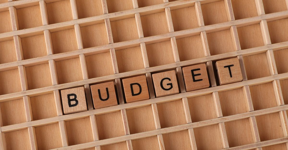 Wooden letter tiles spelling 'budget' on a wooden grid background, symbolizing finance and planning.