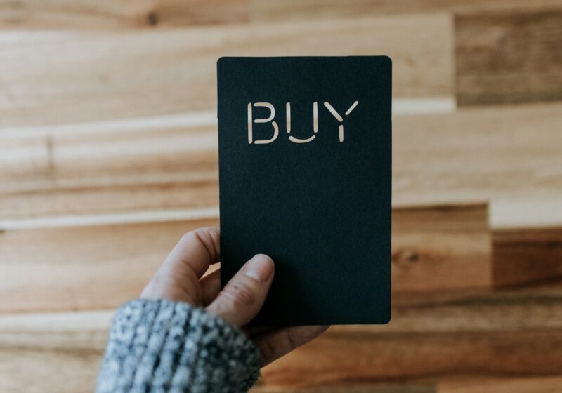 a person holding a black book with the word buy written on it