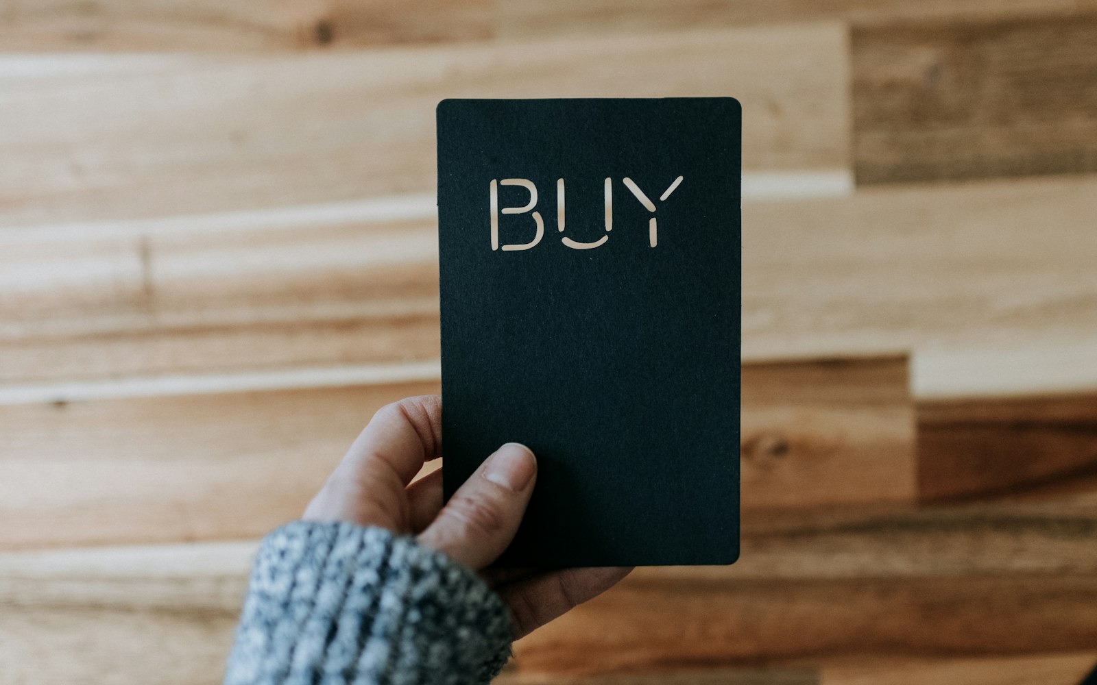 a person holding a black book with the word buy written on it