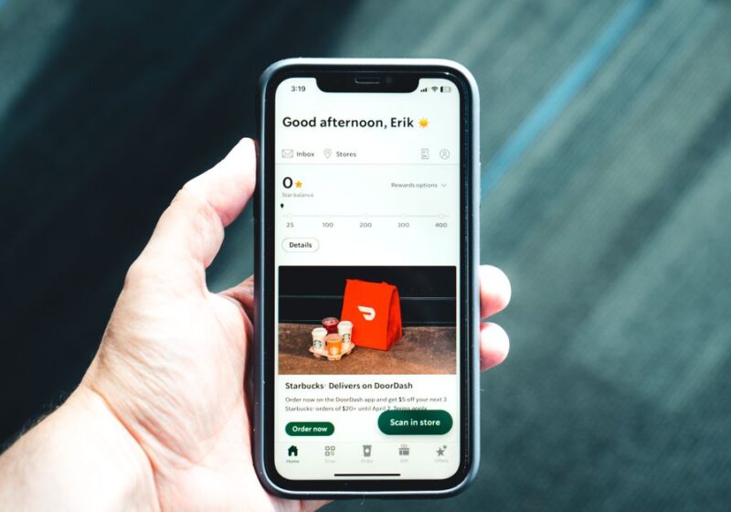 Close-up of a smartphone with a delivery app interface in a person's hand, emphasizing modern e-commerce.
