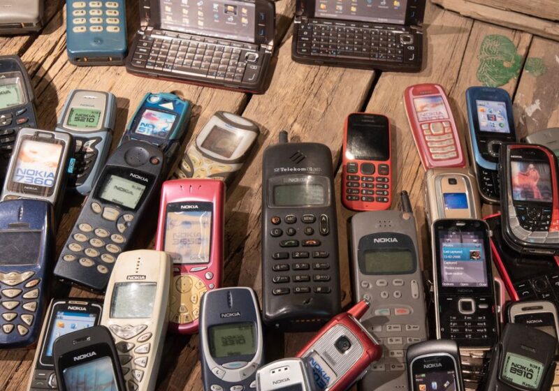 An assortment of retro mobile phones displayed on a rustic wooden surface, showcasing nostalgia.