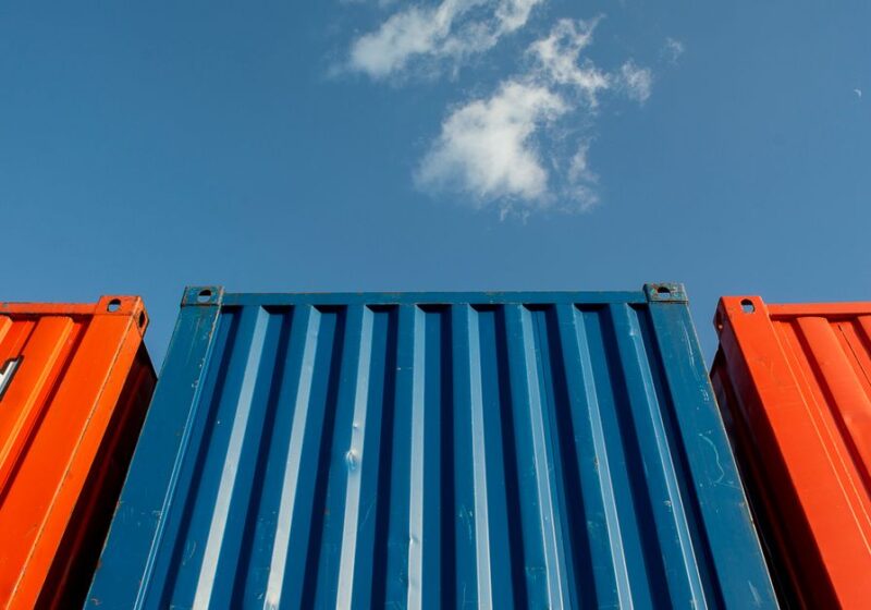 Vibrant red and blue shipping containers under a clear sky, perfect for industrial themes.