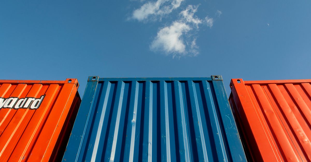 Vibrant red and blue shipping containers under a clear sky, perfect for industrial themes.
