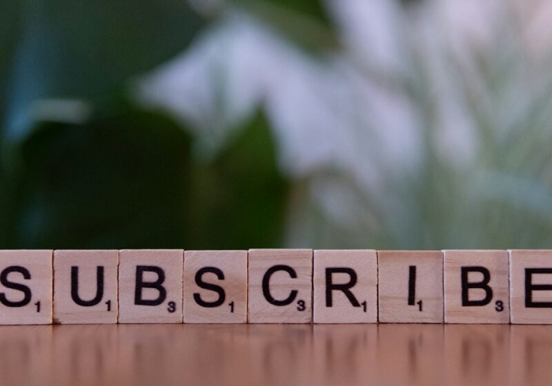 A wooden block spelling subscribe on a table
