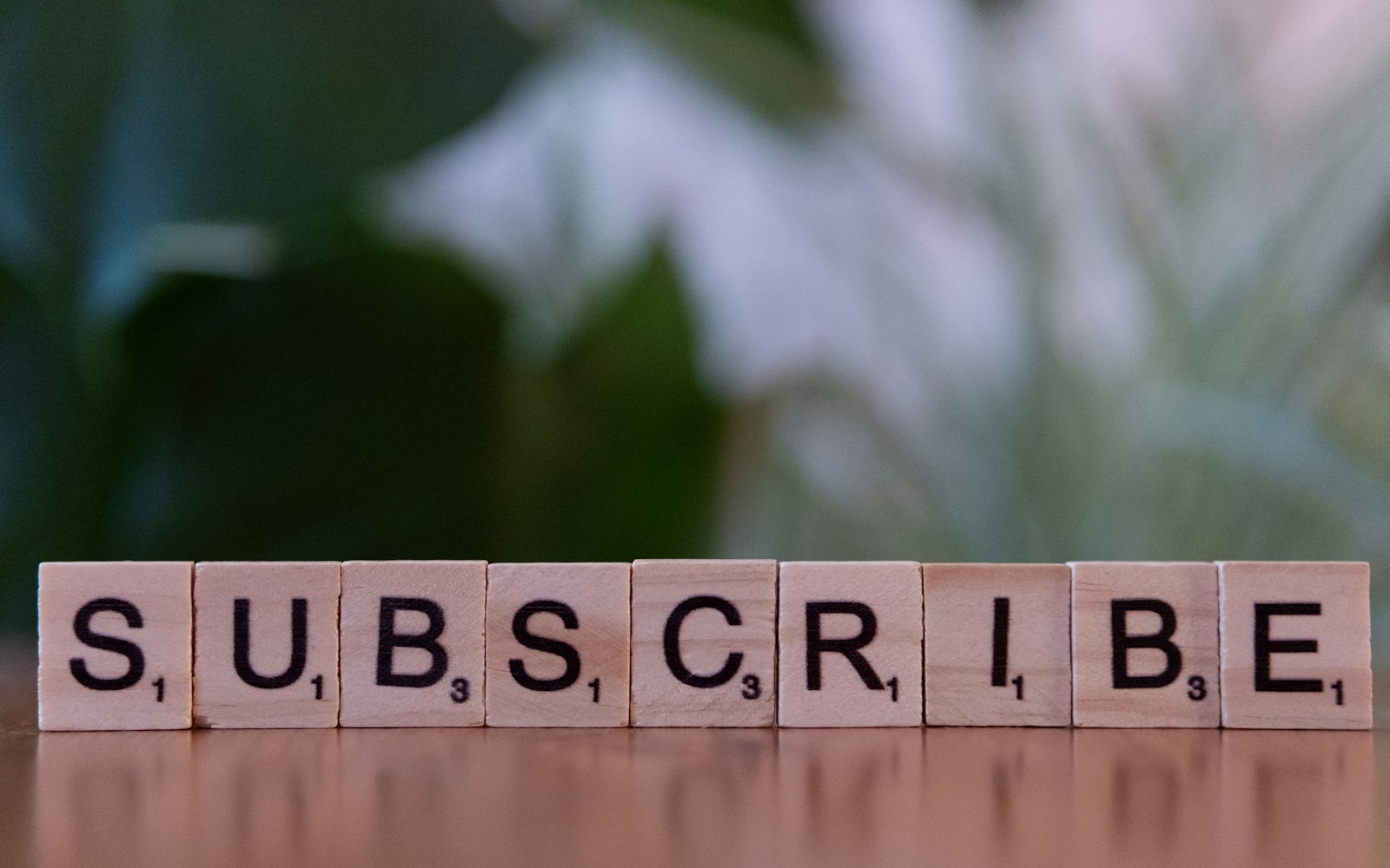 A wooden block spelling subscribe on a table