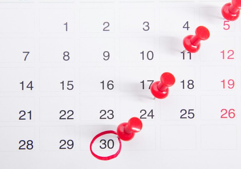 a calendar with red push buttons pinned to it