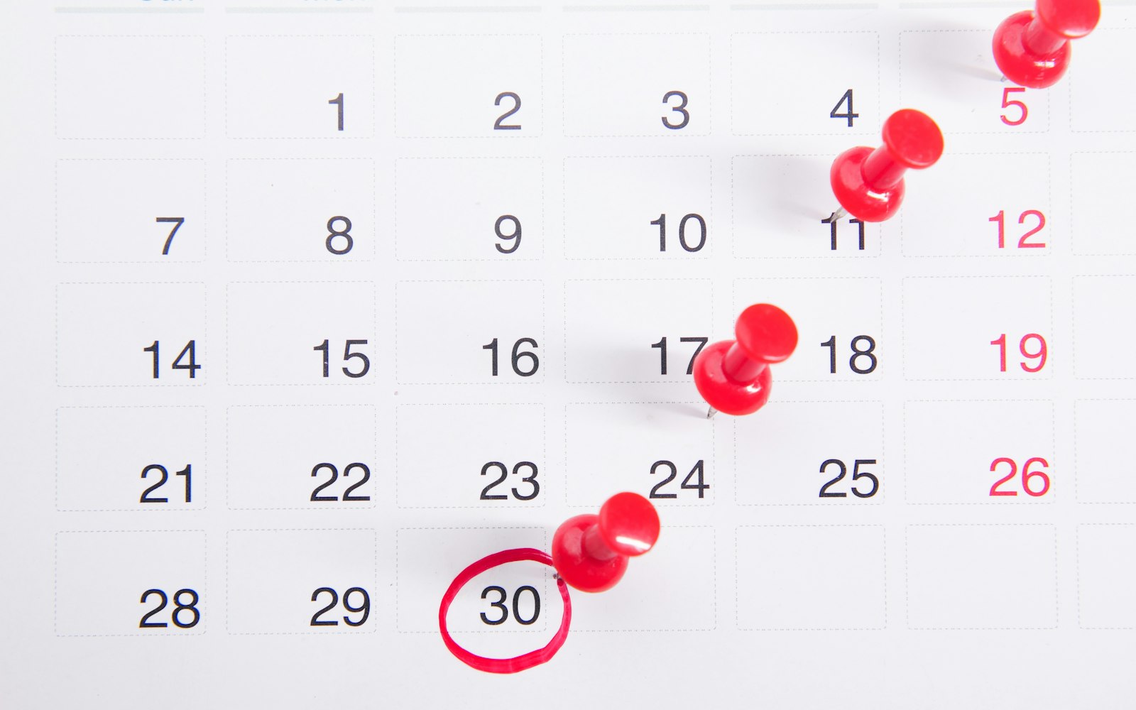 a calendar with red push buttons pinned to it