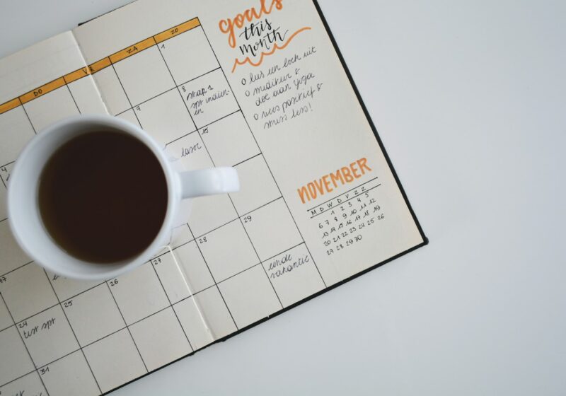 white ceramic mug with coffee on top of a planner