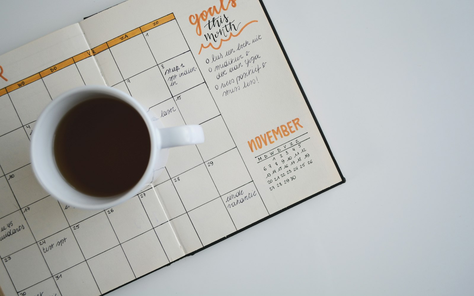 white ceramic mug with coffee on top of a planner