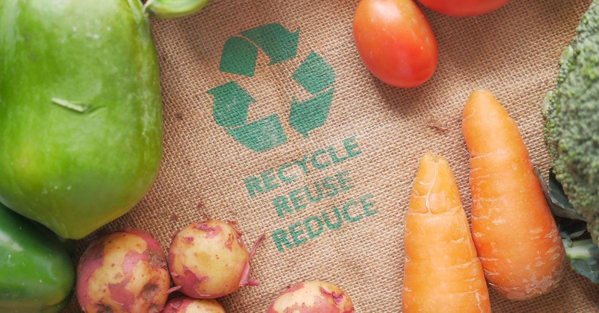 Fresh vegetables on a burlap bag with recycle symbol, promoting eco-friendly choices.