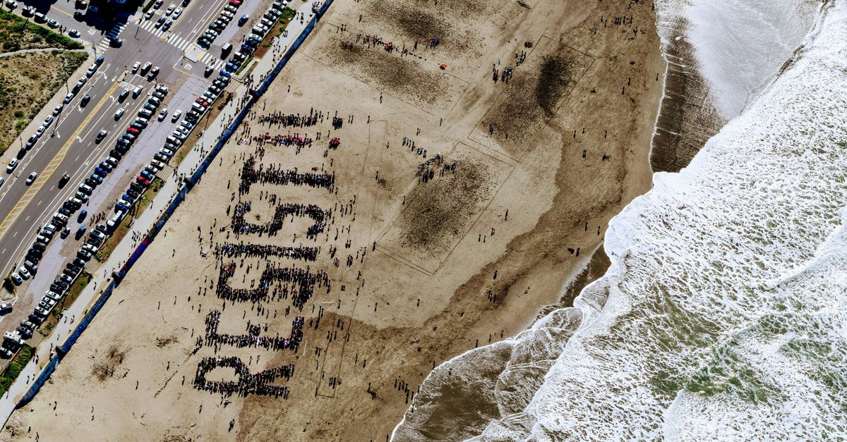 A large group on a beach forms the word "Resist" in powerful demonstration.