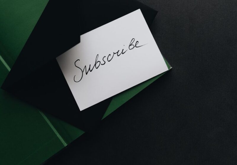 A minimalist image of a 'Subscribe' card in a green envelope on a dark background.