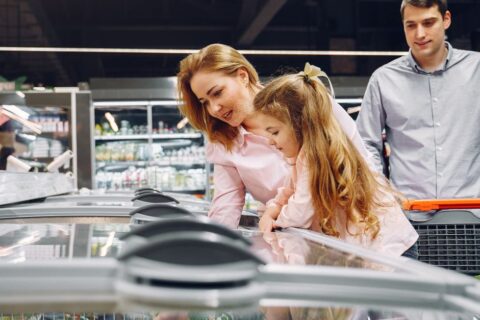 A happy family shopping in the supermarket's freezer section, emphasizing togetherness and love.