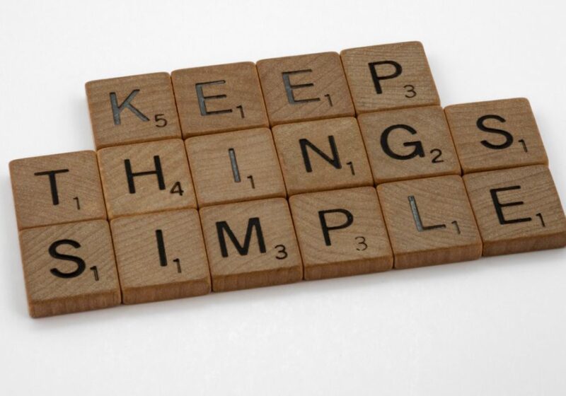 Motivational phrase 'Keep Things Simple' spelled out with wooden Scrabble tiles on a white background.