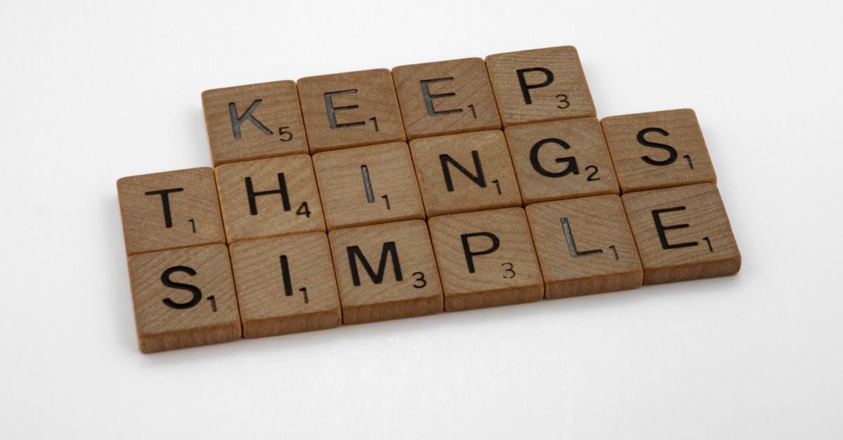 Motivational phrase 'Keep Things Simple' spelled out with wooden Scrabble tiles on a white background.