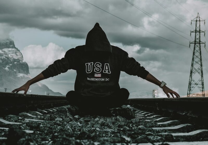 a person sitting on a train track with their arms outstretched