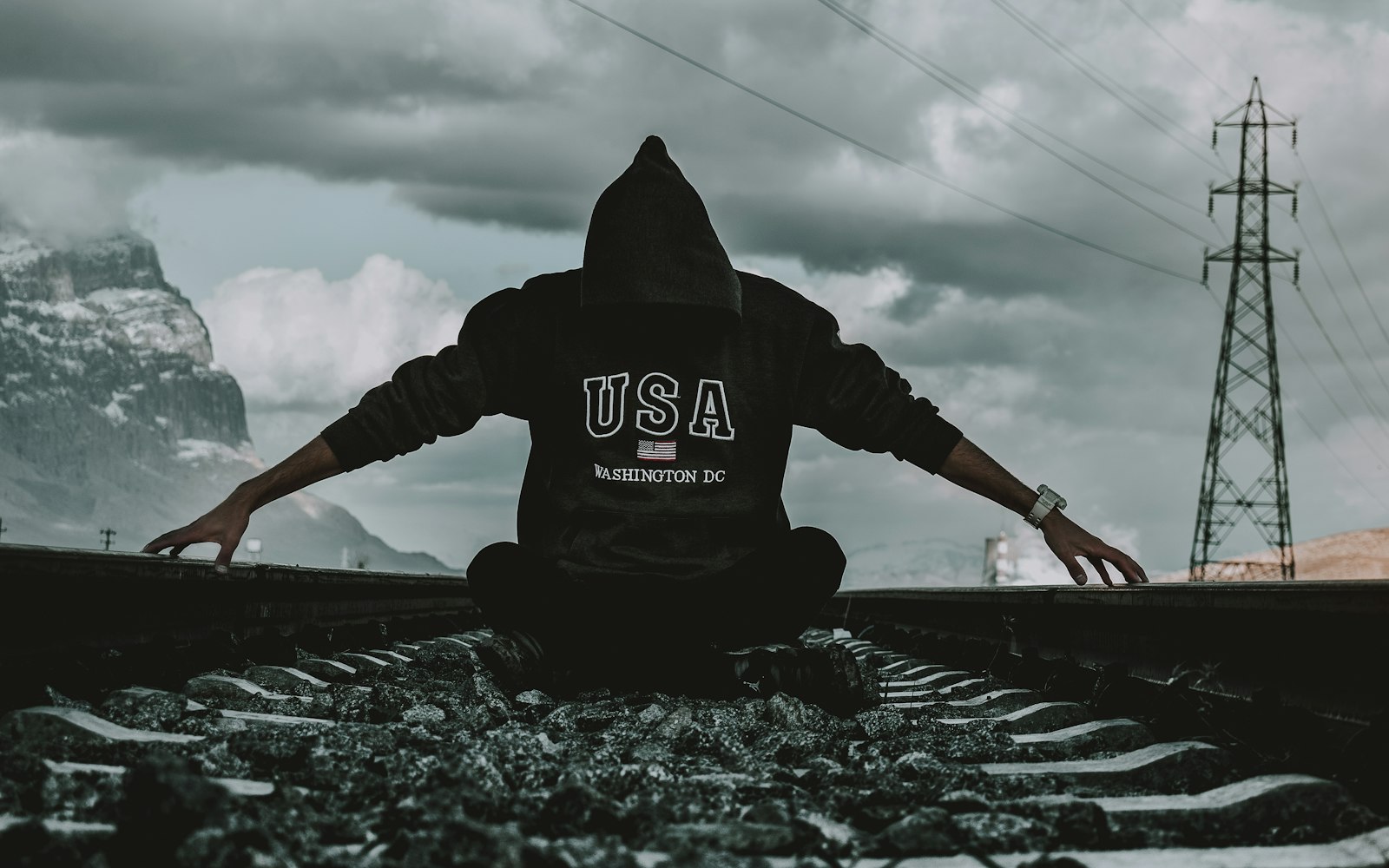 a person sitting on a train track with their arms outstretched