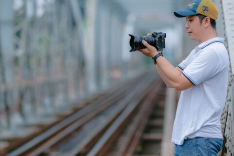 A photographer on a railway bridge capturing scenic moments with his camera.