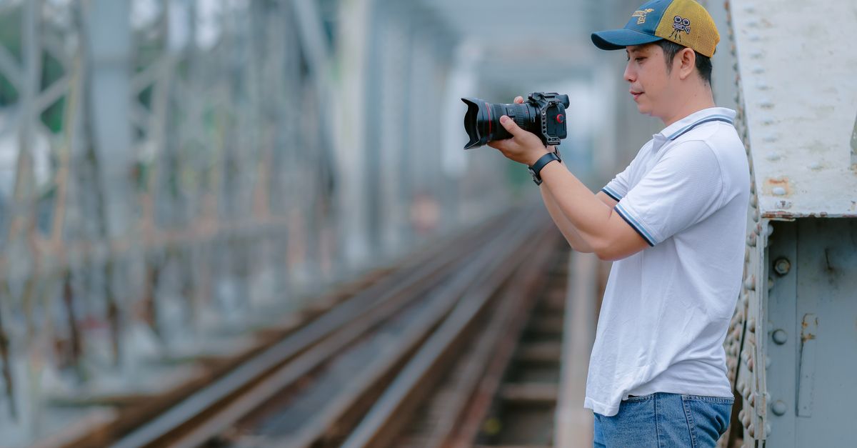 A photographer on a railway bridge capturing scenic moments with his camera.