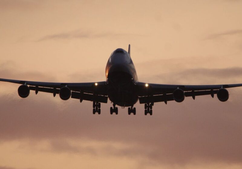 A passenger airplane silhouetted against a vibrant sunset sky, capturing the essence of travel.