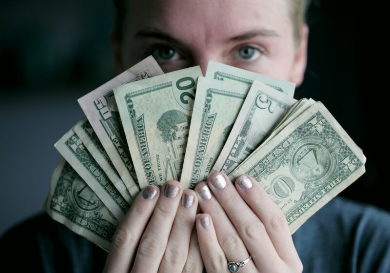 person holding fan of U.S. dollars banknote