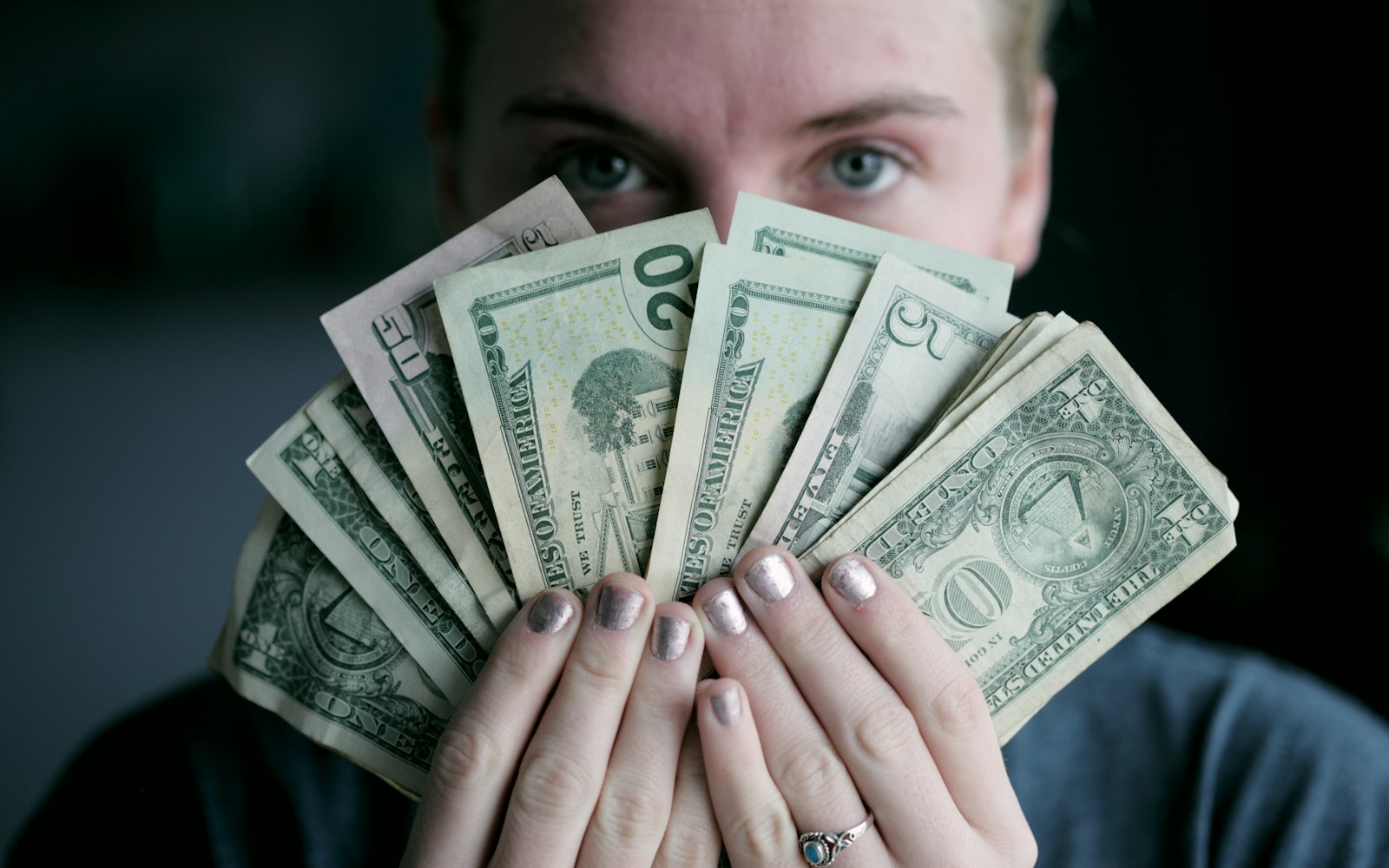 person holding fan of U.S. dollars banknote