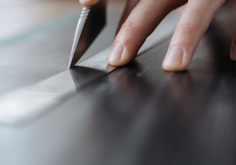 Detailed close-up of hands cutting with knife and ruler, perfect for design and crafting themes.
