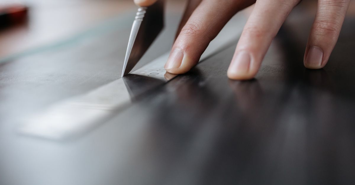 Detailed close-up of hands cutting with knife and ruler, perfect for design and crafting themes.
