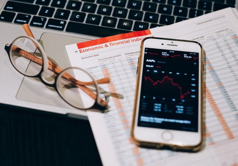 A detailed look at financial tools including a smartphone and laptop for stock analysis.