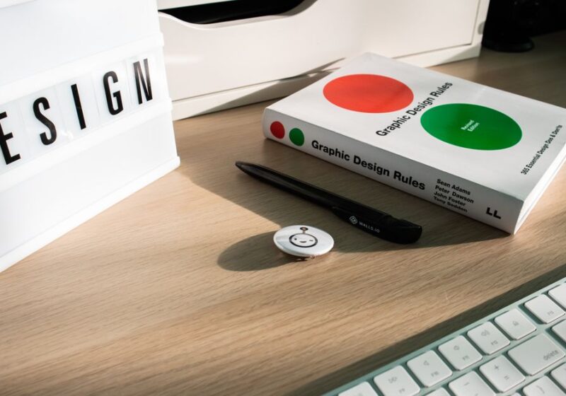 A modern desk setup featuring design elements like a book, #DESIGN sign, and accessories.